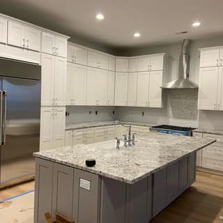 Finished kitchen remodel with white shaker cabinetry, granite island, and stainless appliances