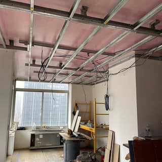 Fire-rated drywall going up on a metal-stud ceiling grid in a Manhattan high-rise build-out