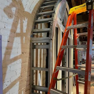Metal framing fitted to a curved brick archway during an interior renovation