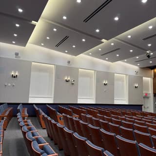 Completed auditorium fit-out with tiered seating, coffered ceiling, and wall sconces